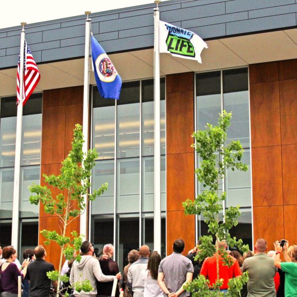 Group of people raising the Donate Life flag in front of the LifeSource building